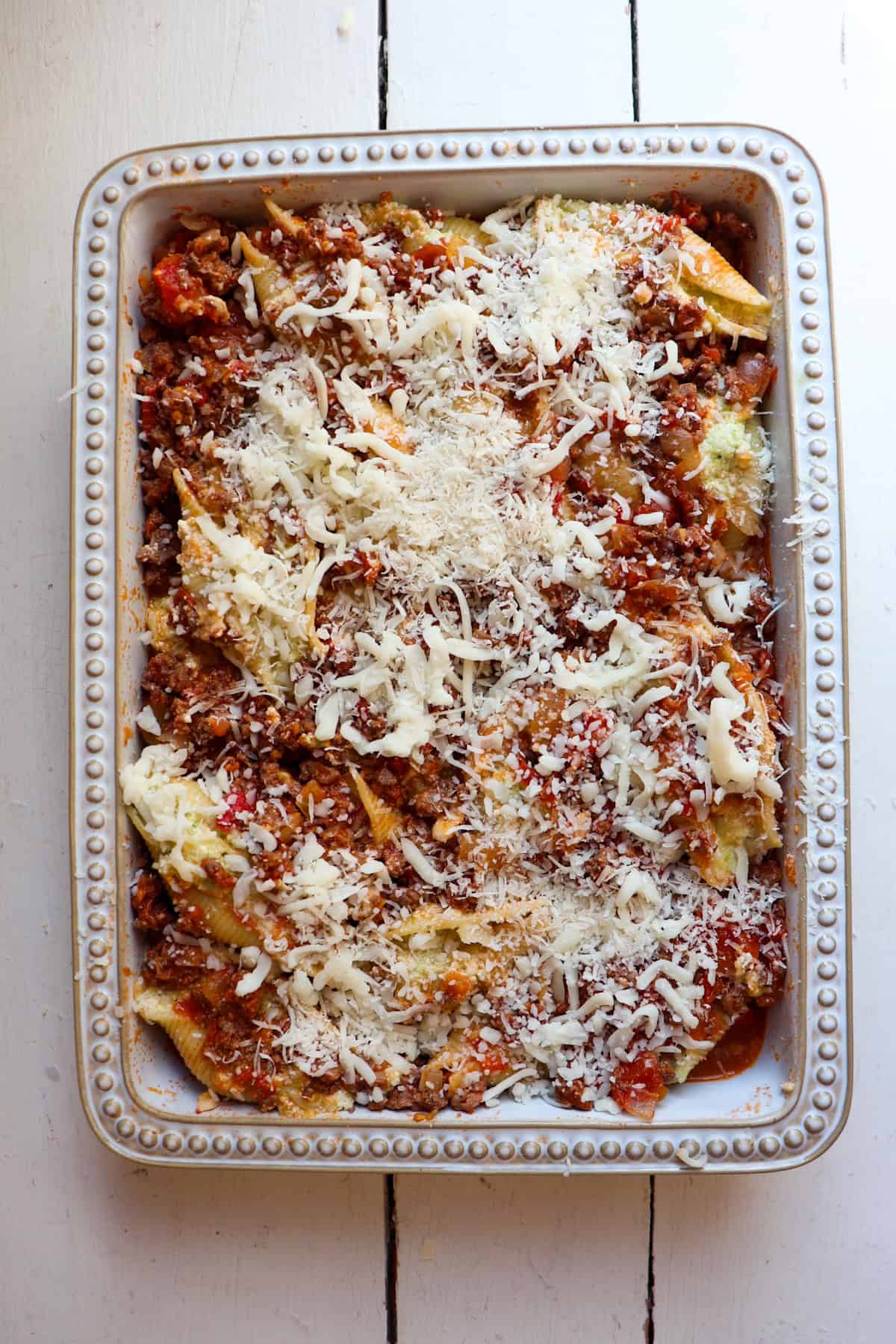 stuffed shells topped with cheese in baking pan.
