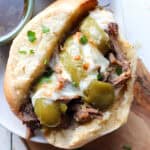 up close of finished slow cooker italian beef sandwich on a wooden board.