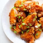 featured image of soy garlic chicken wings with scallions on a white plate.
