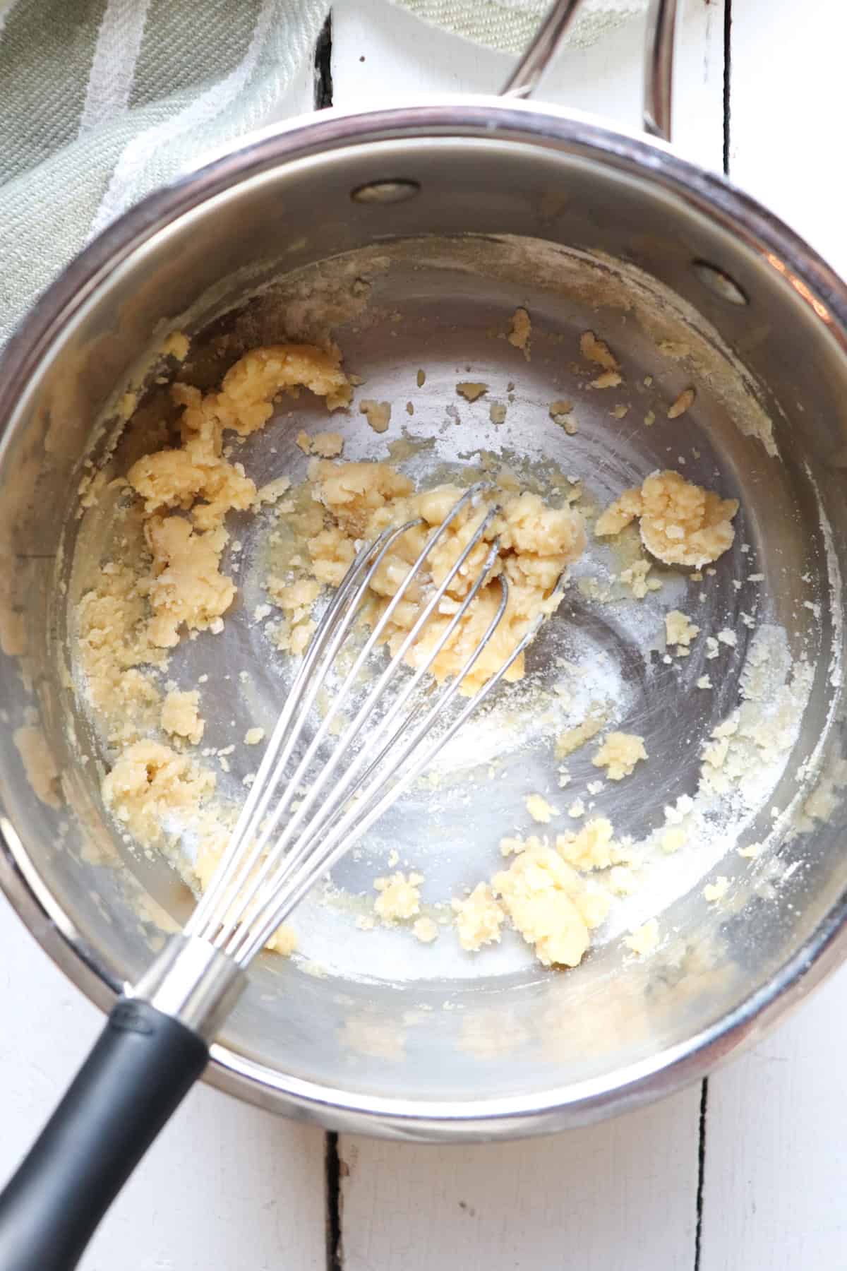 butter and flour combine to make a roux in a pot.