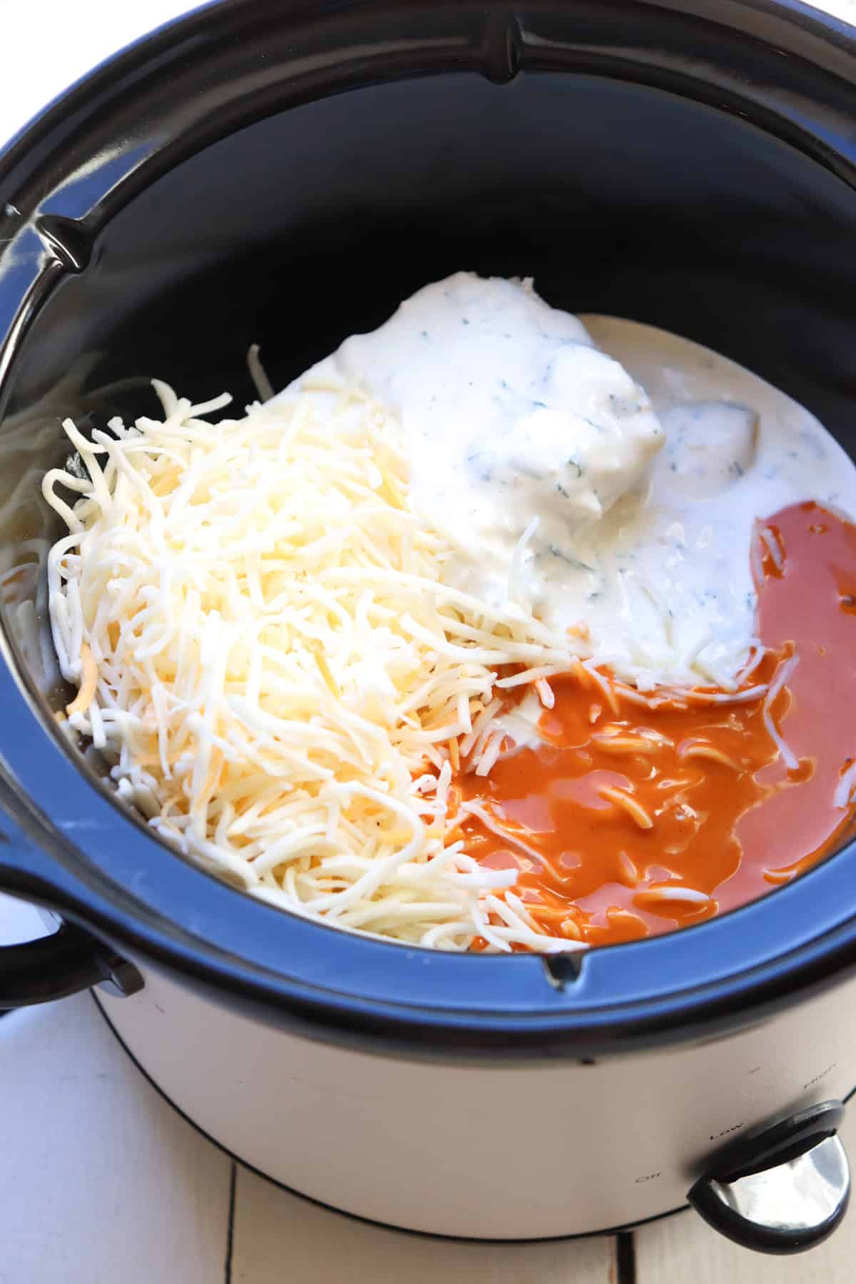 ingredients in slow cooker for buffalo chicken dip.