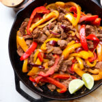 cast iron skillet filled with venison fajitas.