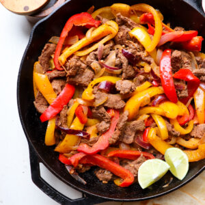 cast iron skillet filled with venison fajitas.