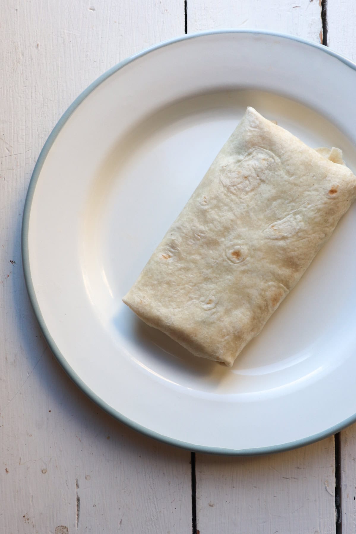 breakfast burrito on white plate.