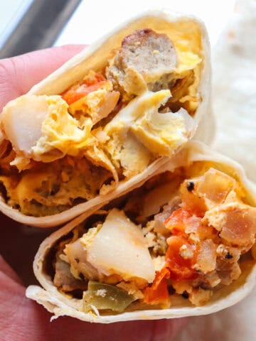 hand holding breakfast burrito with potoatoes.