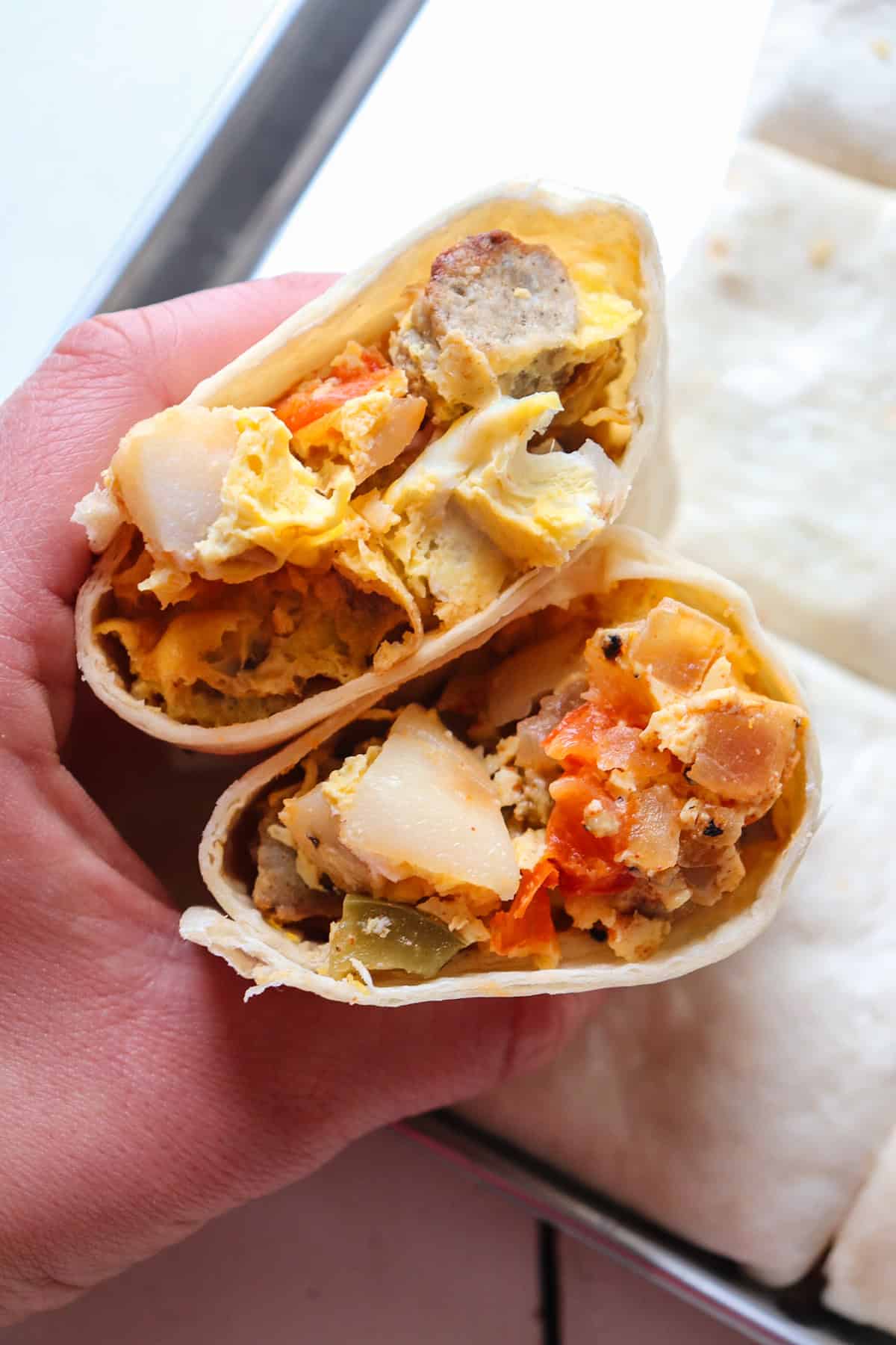 hand holding sheet pan breakfast burrito.