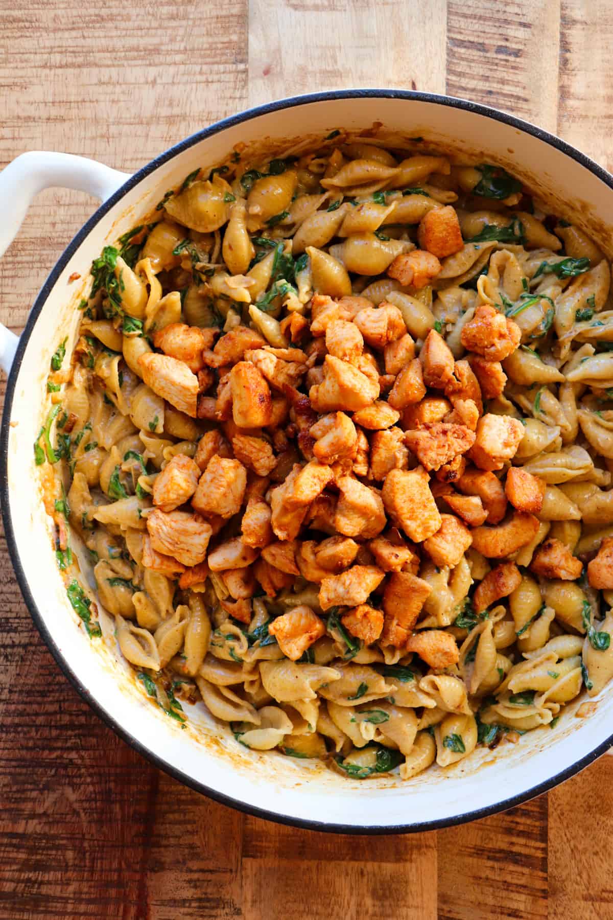 pasta in cooking pot with chicken on top.