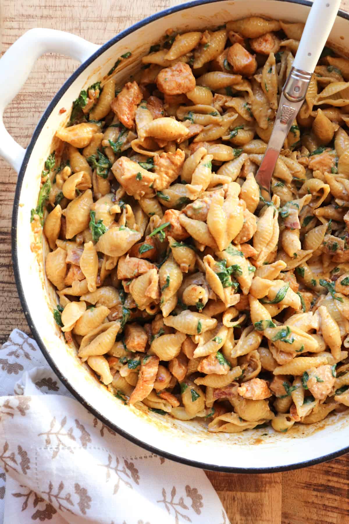 creamy chicken and garlic pasta in pot with serving spoon.