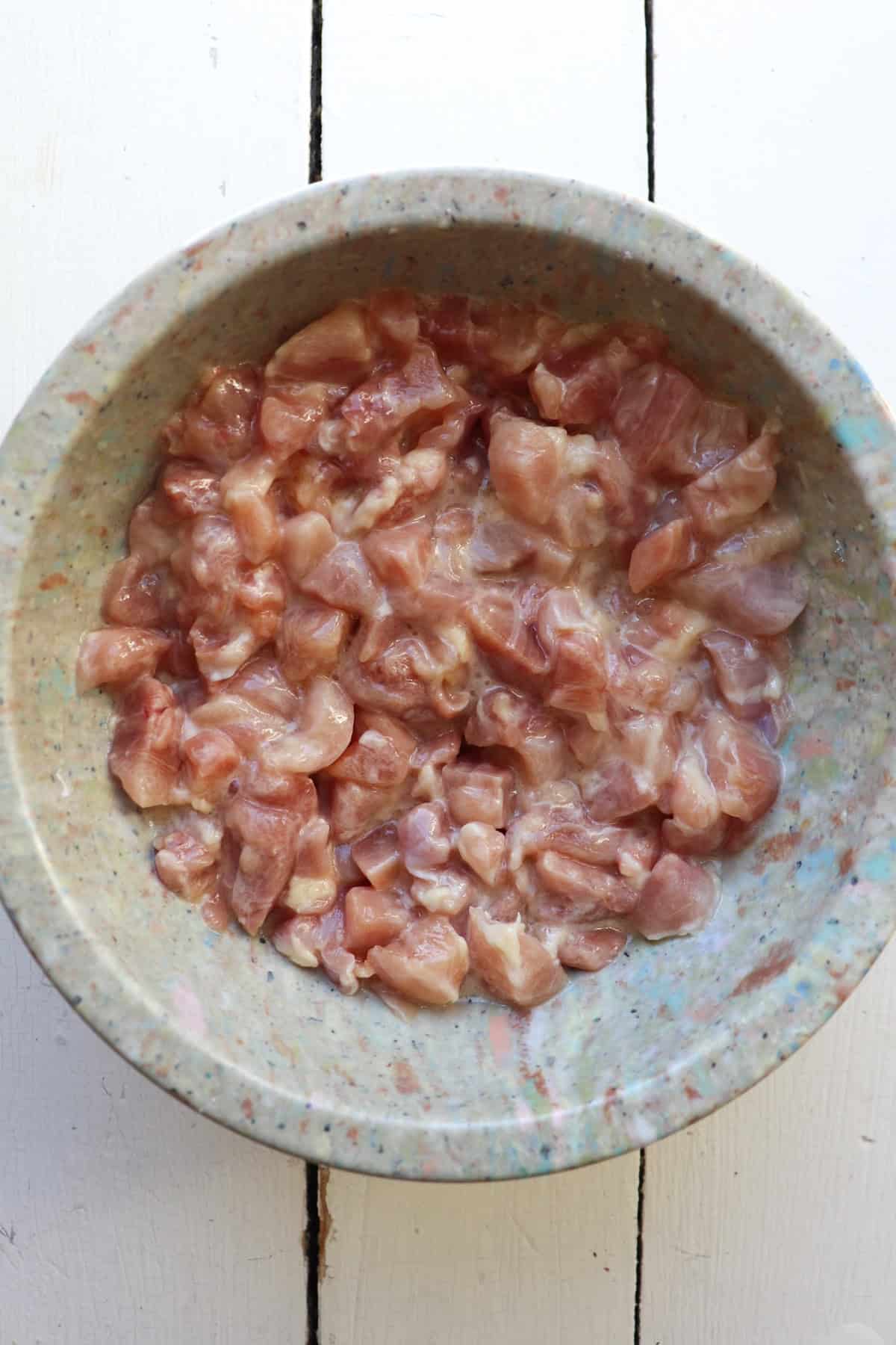 chicken thigh pieces marinating in bowl.