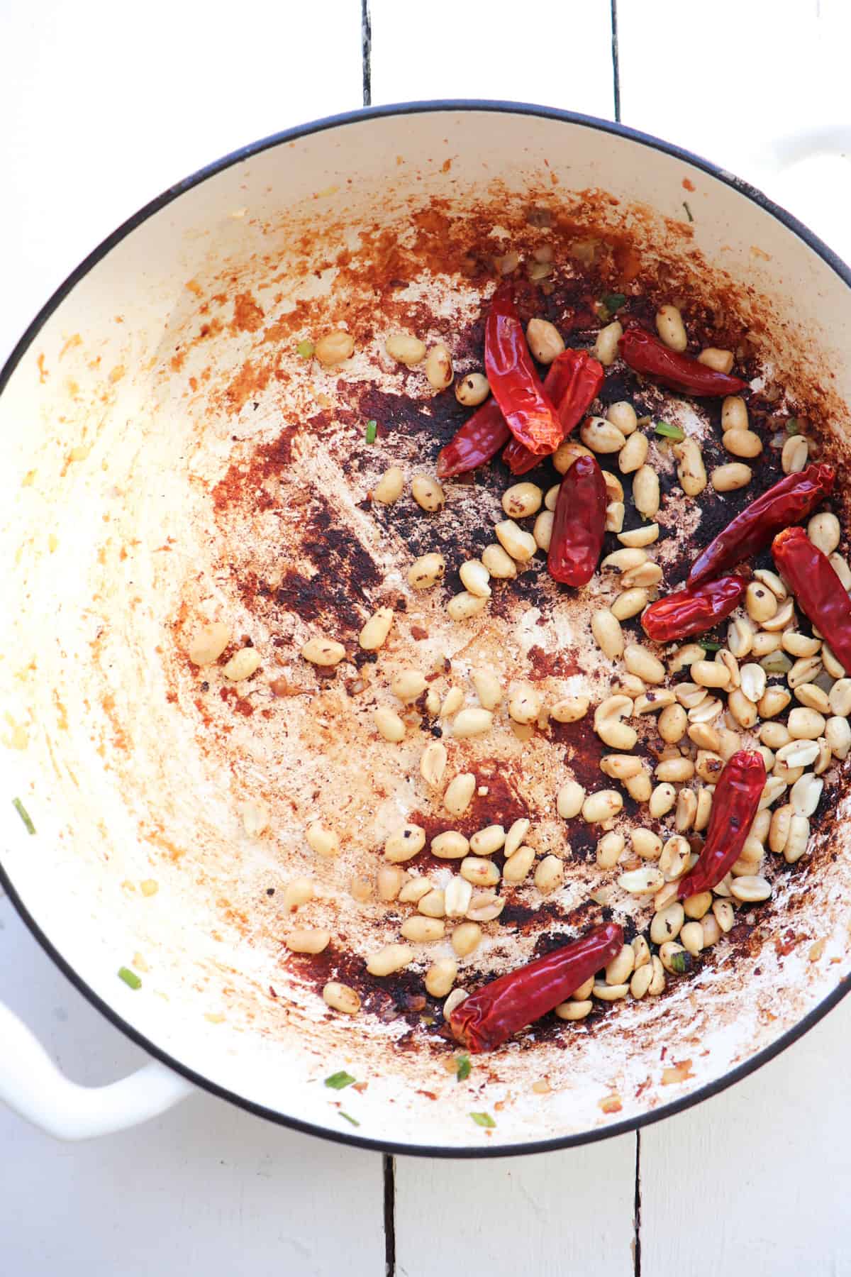 peanuts and chilis in white skillet.