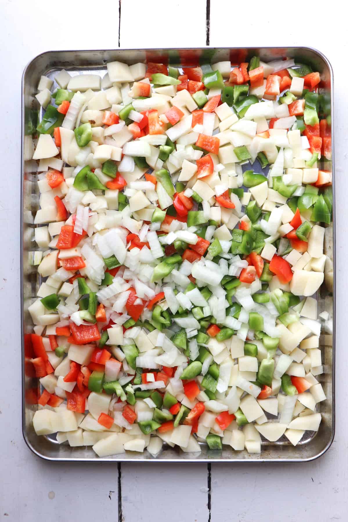 sheet pan of raw vegetables for breakfast burritos.