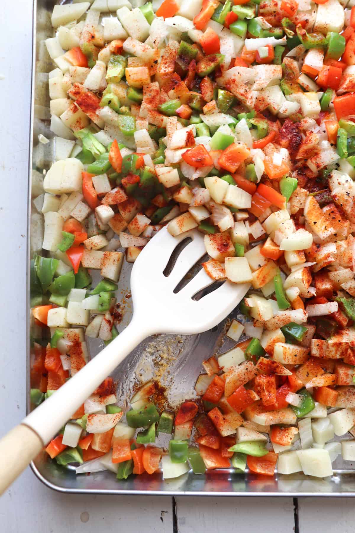 spatula mixing sheetpan vegetables for breakfast burritos.