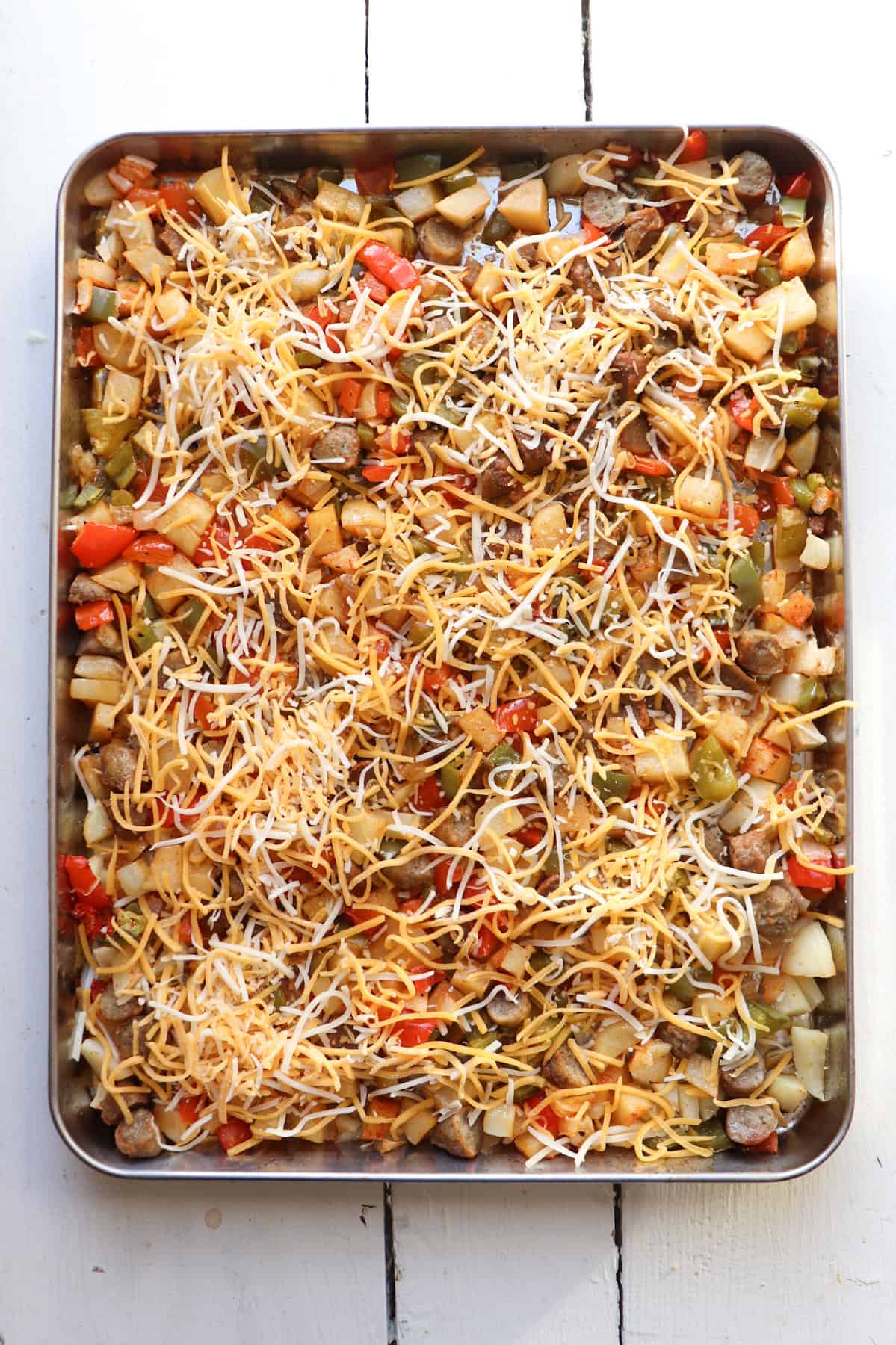cheese topped sheet pan with vegetables and potatoes.