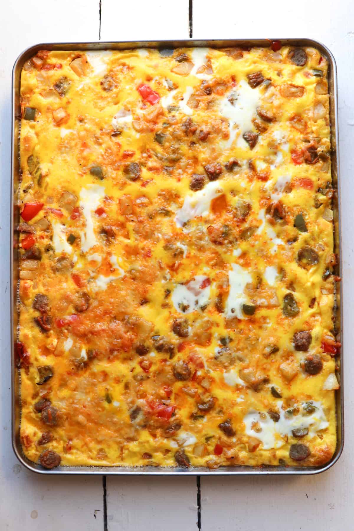 sheetpan with baked eggs, vegetables, and potatoes.