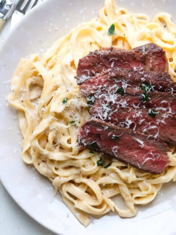 steak fettuccine alfredo topped with cheese.
