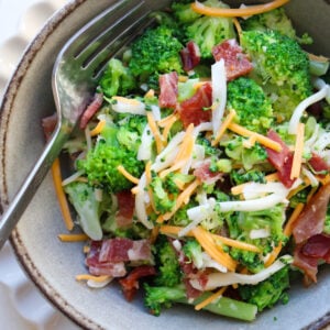bowl of broccoli salad topped with cheese and bacon.