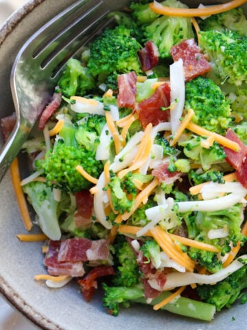 bowl of broccoli salad topped with cheese and bacon.