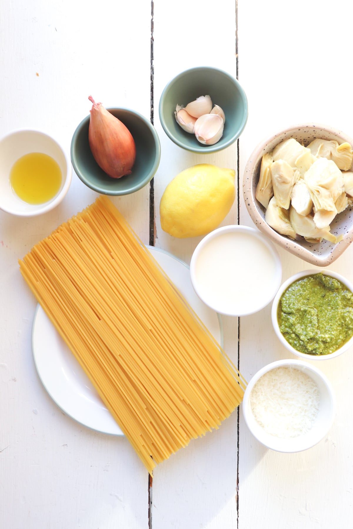 ingredients for pesto artichoke pasta on a white table.