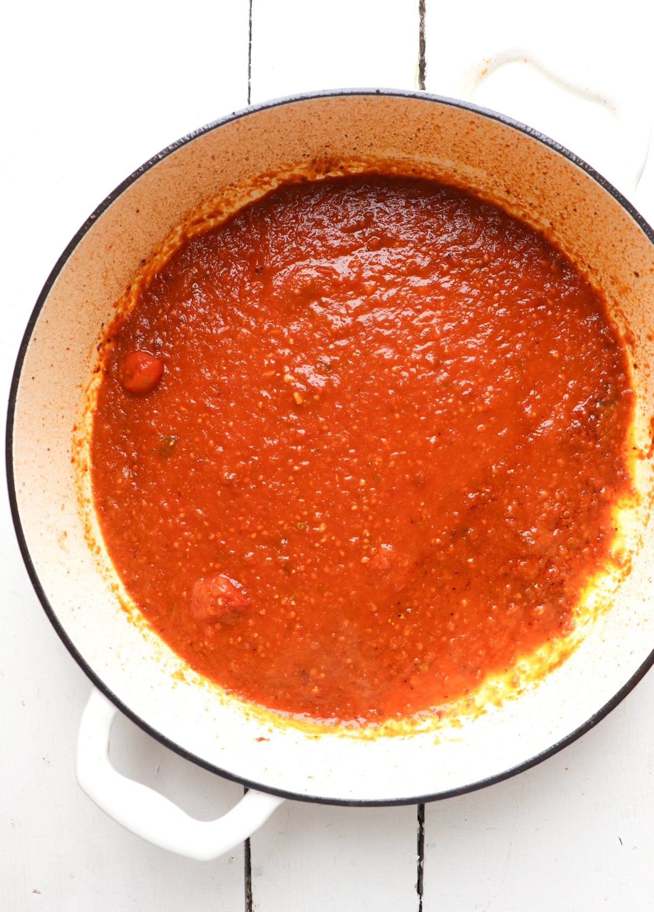 marinara sauce added to white enamel skillet.