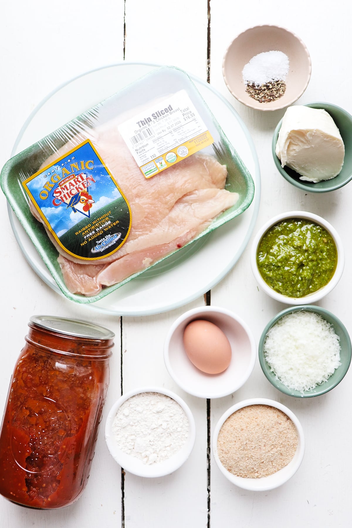 ingredients for pesto chicken parmesan on a white table.