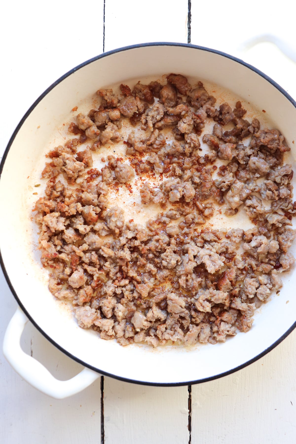 italian sausage browning in a white dutch oven.
