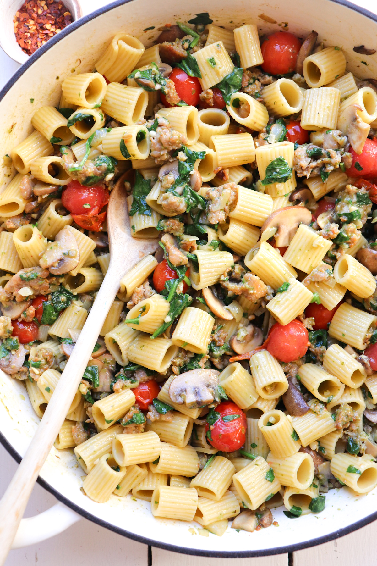 skillet with a wooden spoon scooping pasta.