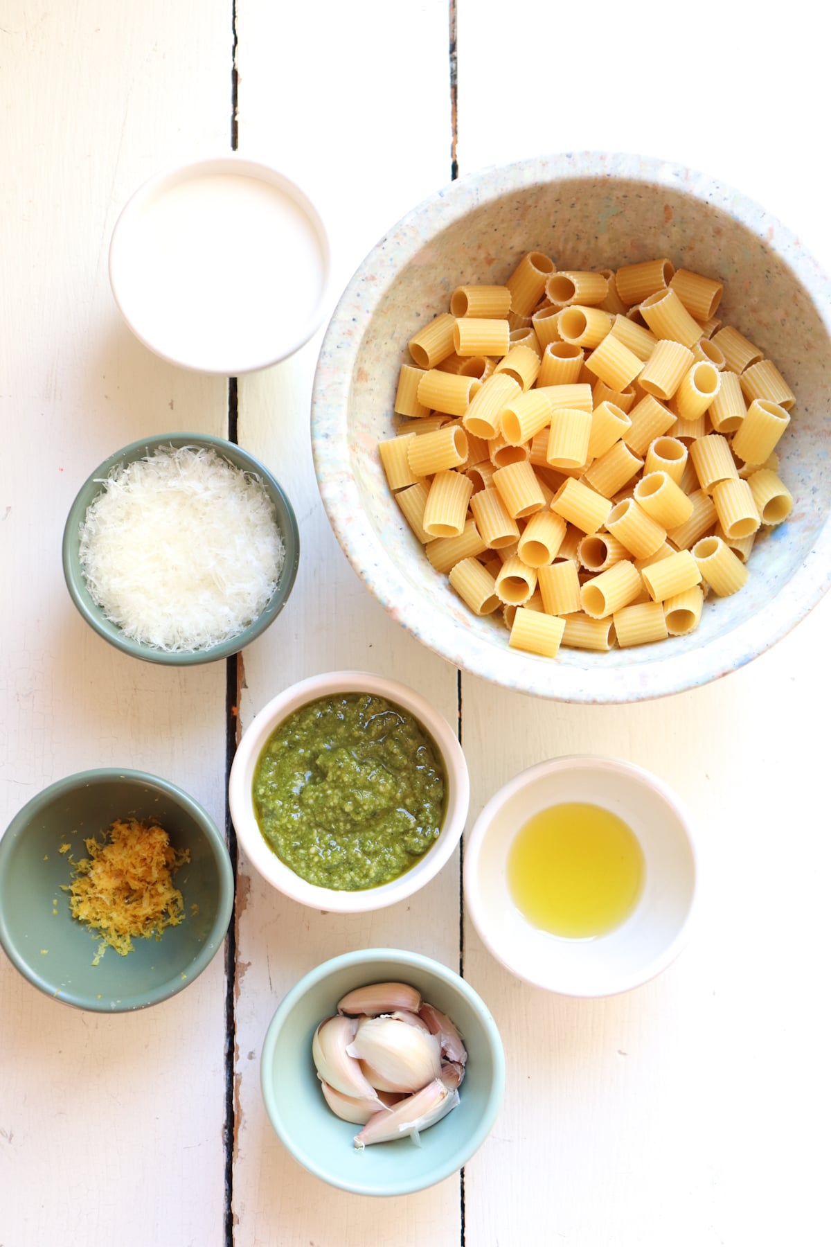 ingredients for garlic pesto pasta on a white table.