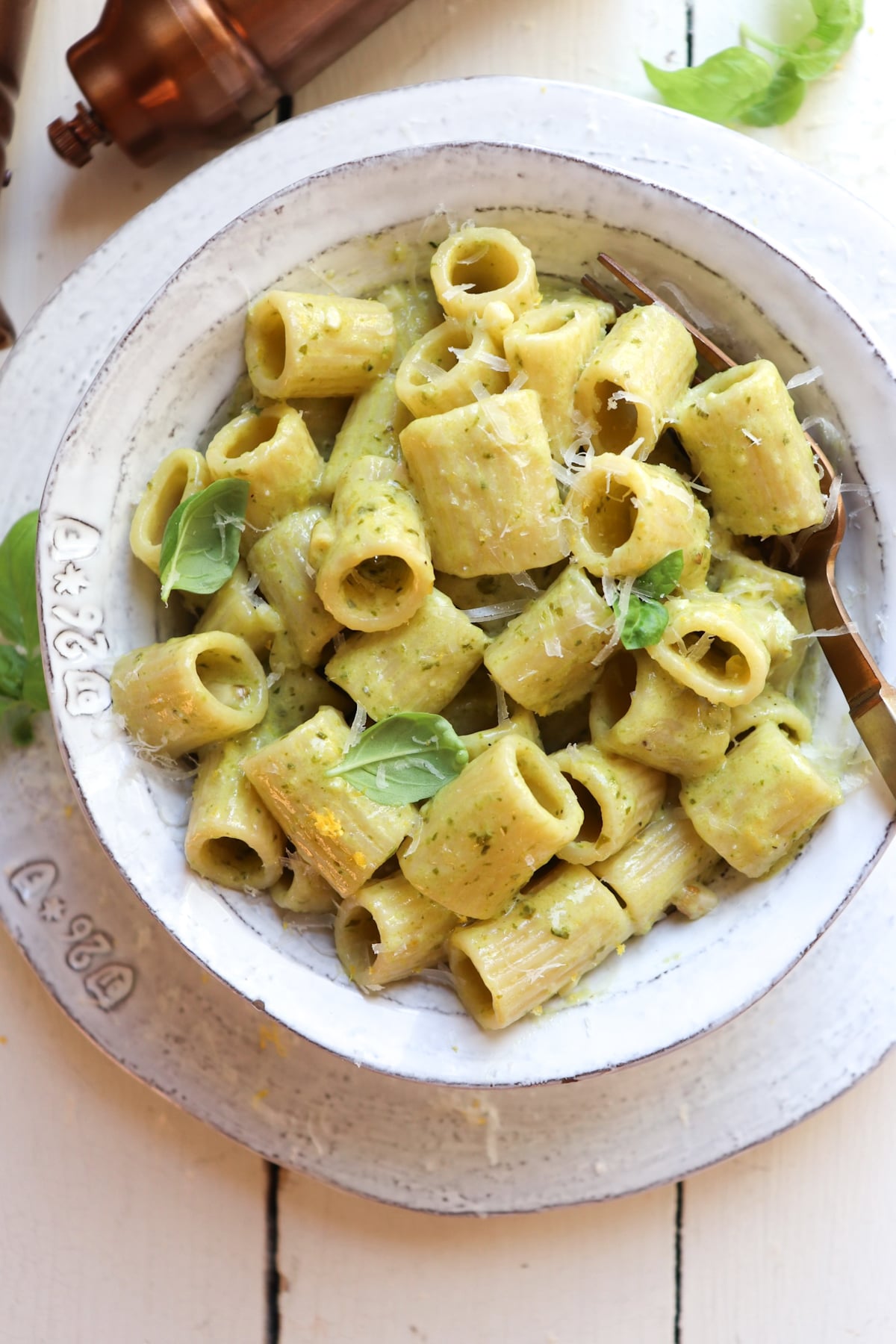 bowl of creamy garlic pesto pasta garnished with basil leaves.