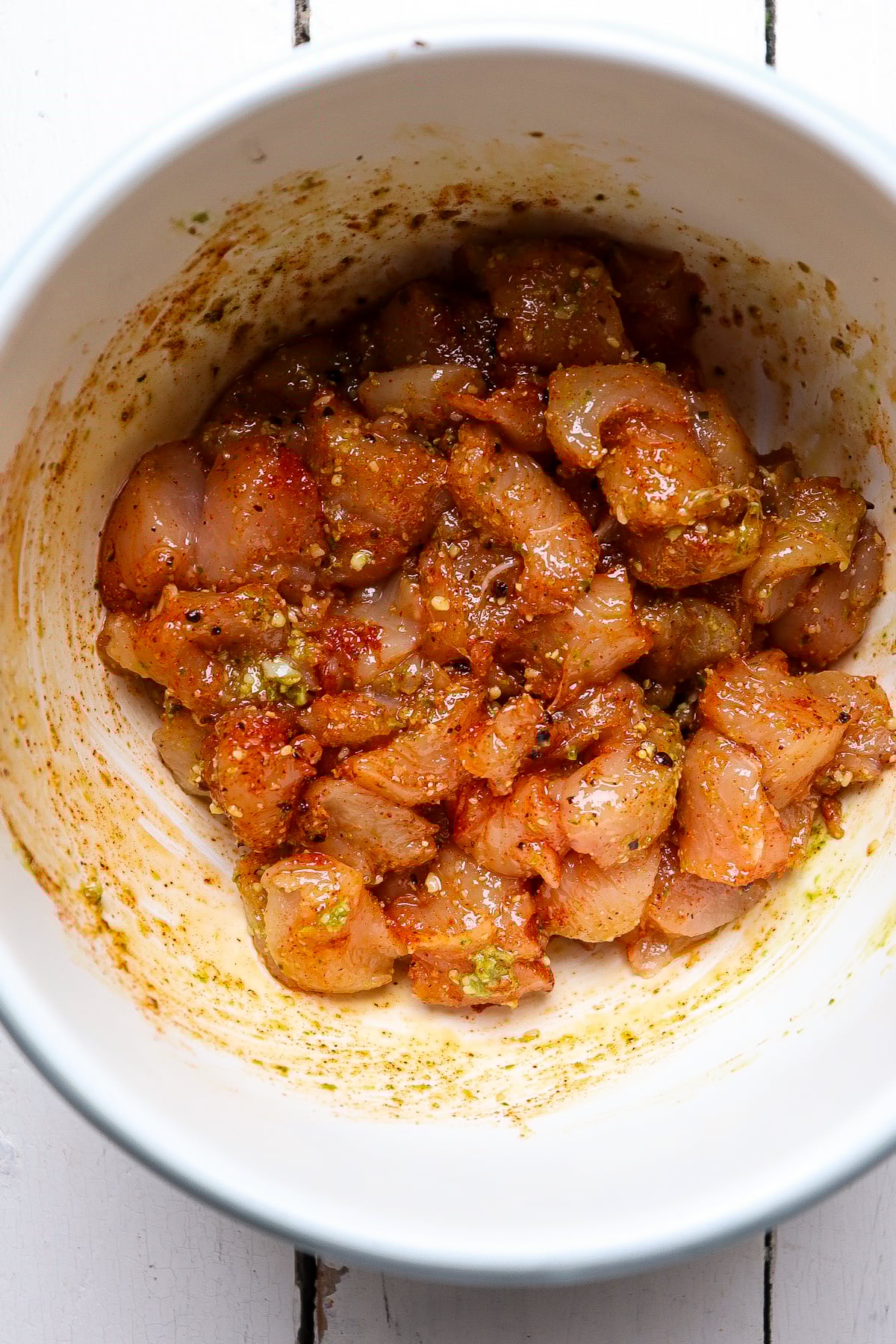 marinating chicken in a white bowl.