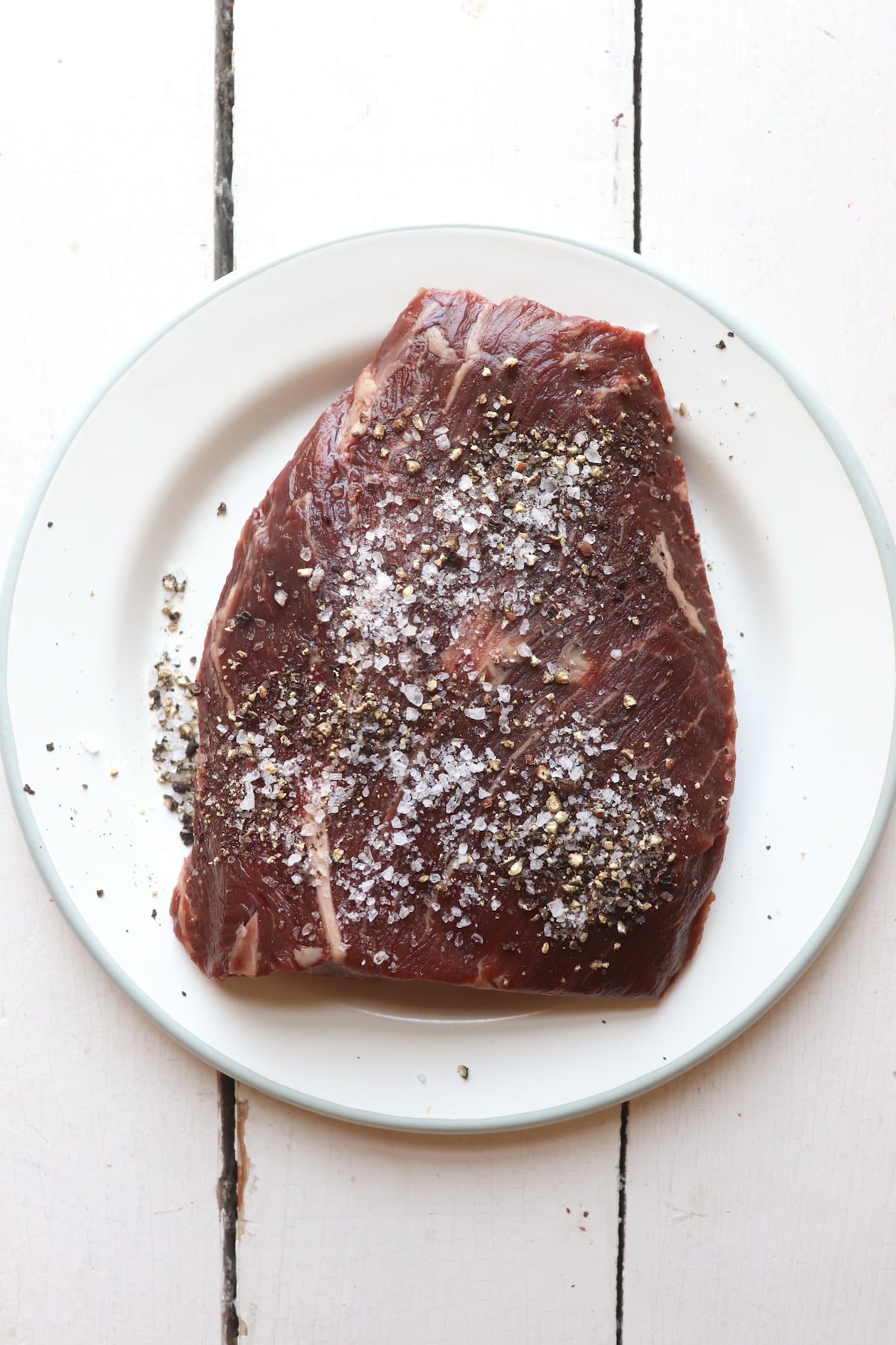 hangar steak seasoned with salt and pepper on a white plate.