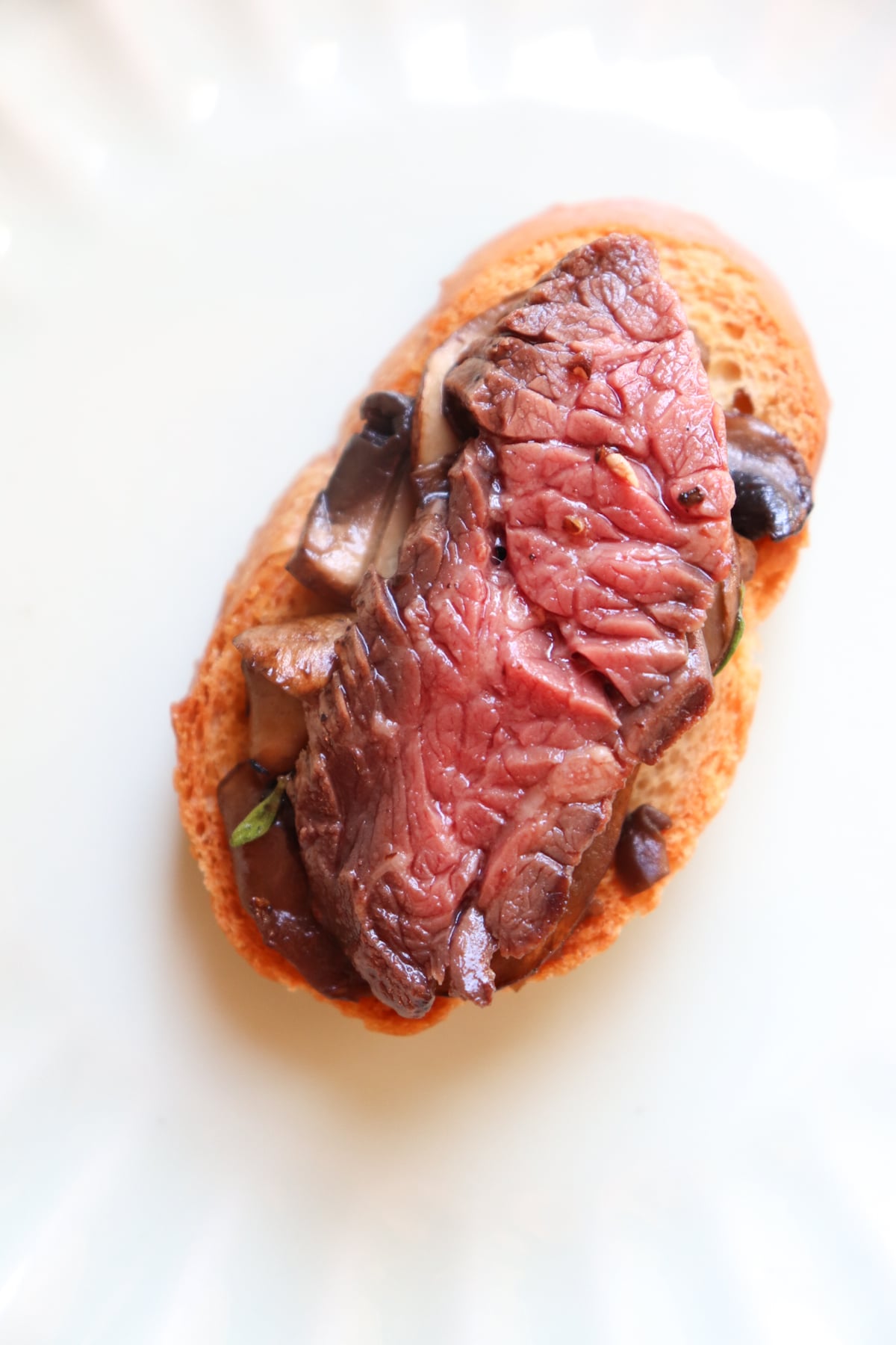 slice of filet mignon on top of sauteed mushrooms and bread crisp.