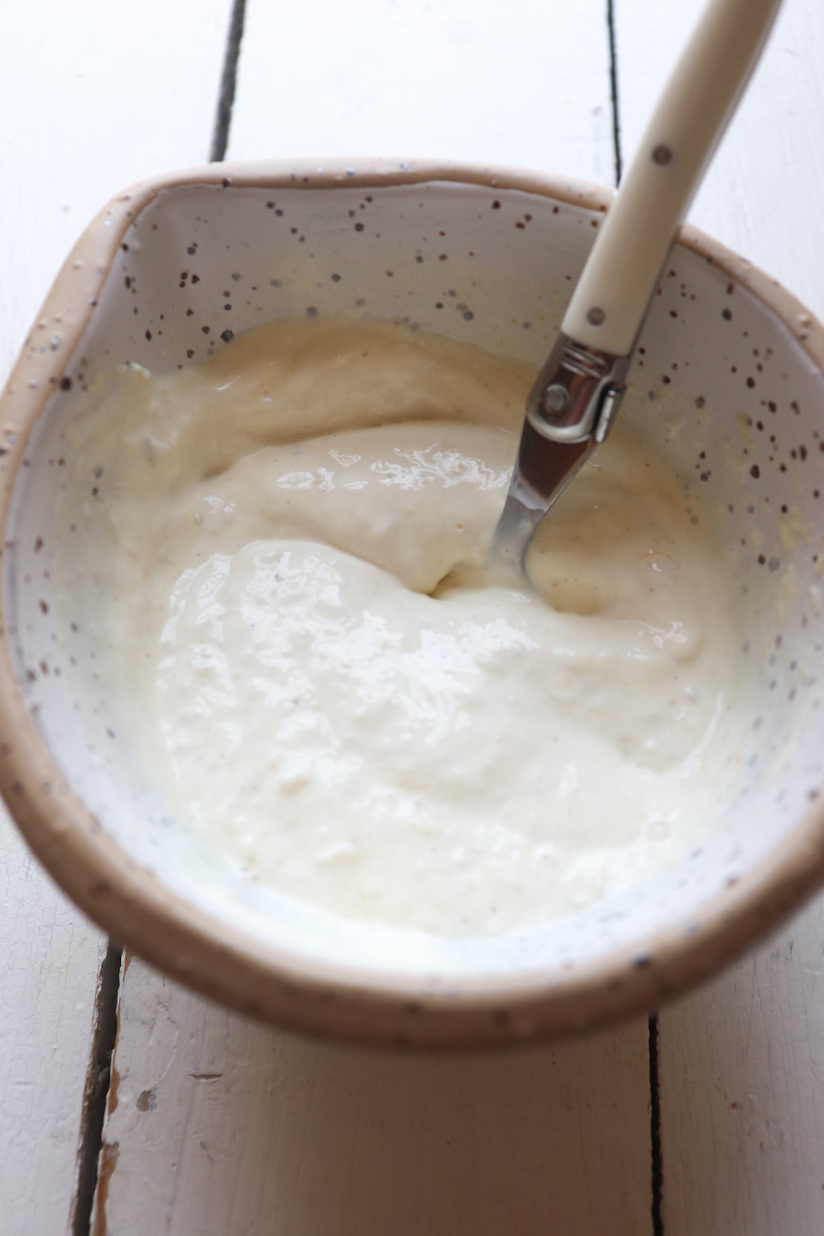 finished horseradish cream stirred with a spoon in a white bowl.