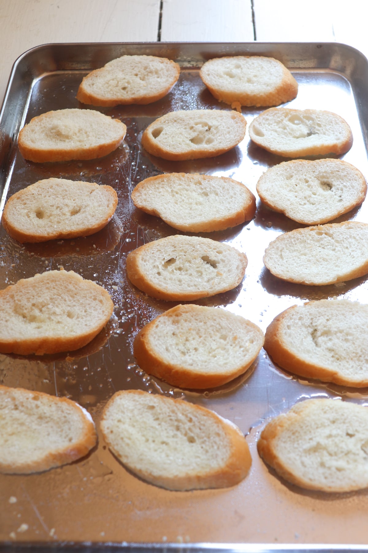 crostini bread pieces lined up on a baking sheet.