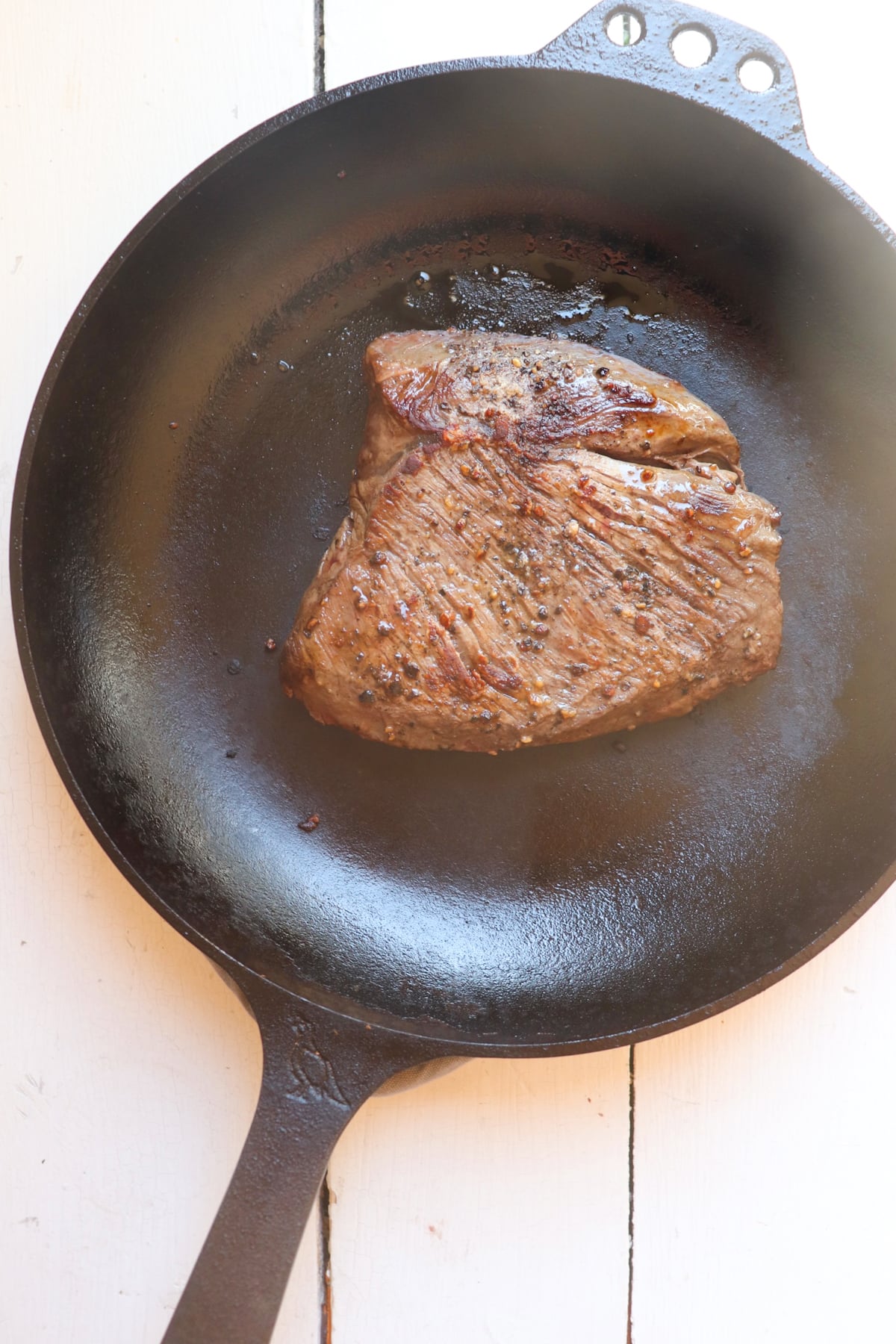hangar steak cooking in a cast iron skillet.