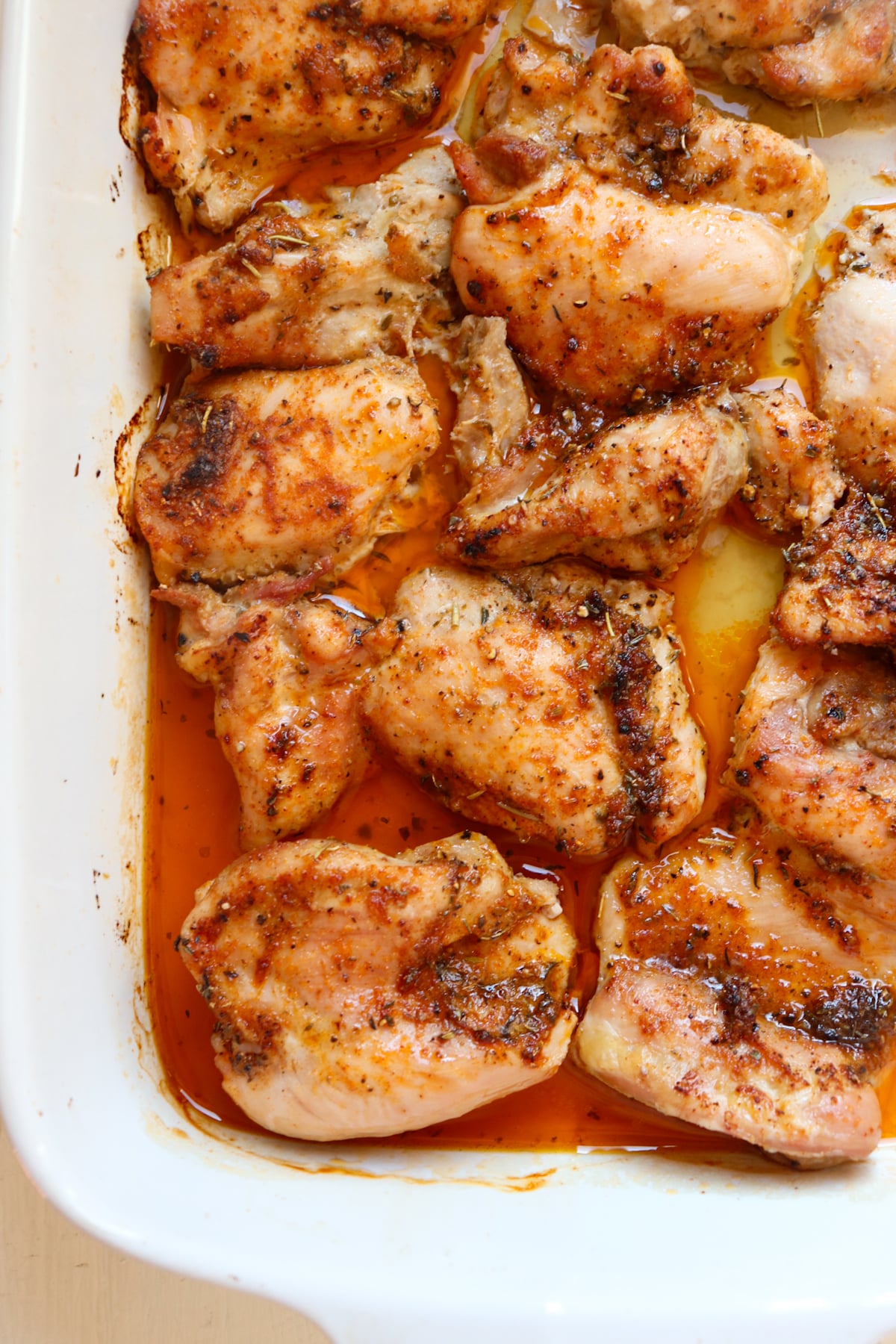 cooked boneless skinless chicken thighs in a white baking dish.