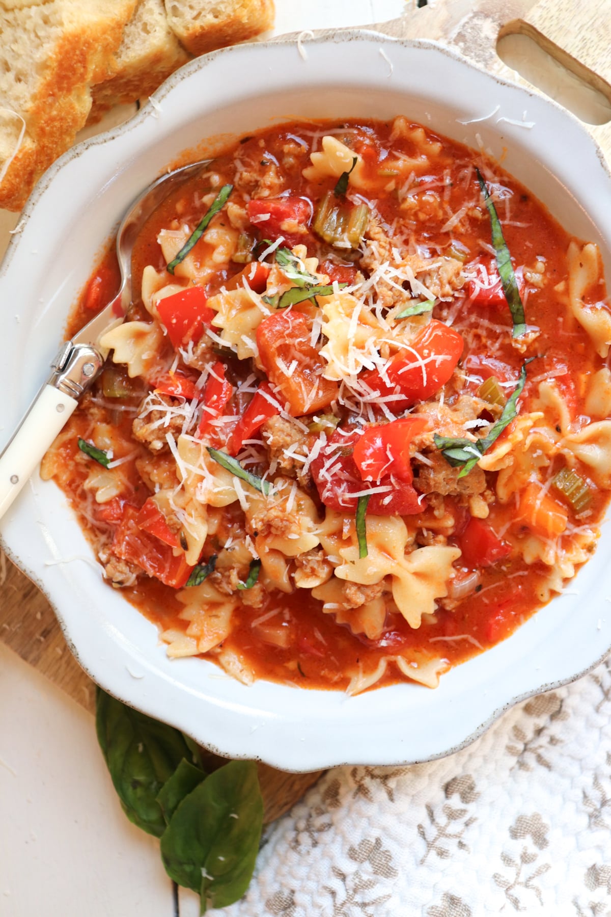 soup shown topped with basil and parmesan with a spoon in the bowl.