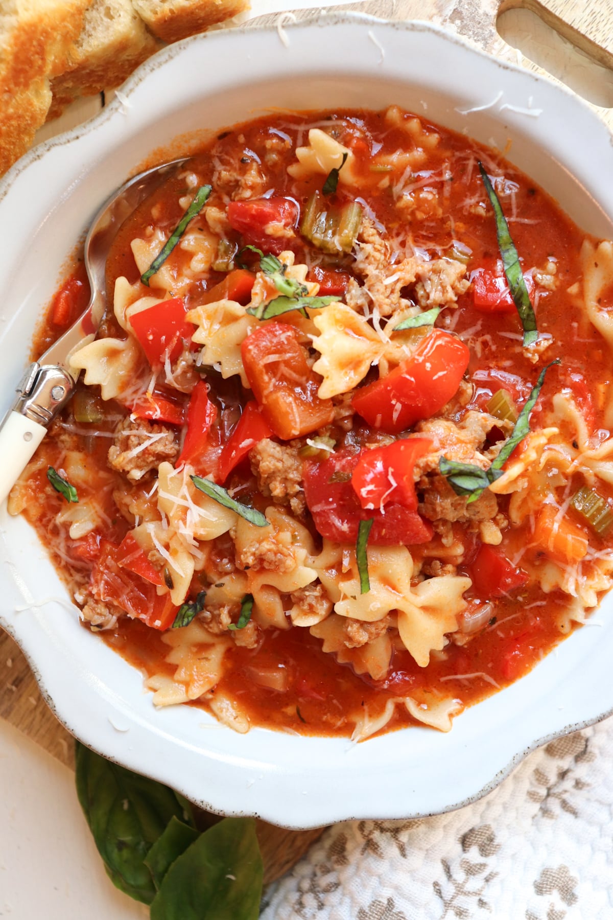 white bowl filled with sausage and pepper soup with garnish.