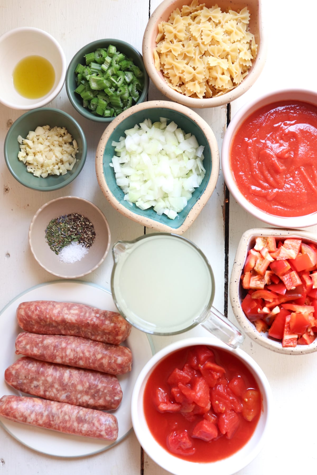 ingredients for sausage and pepper soup on a white table.
