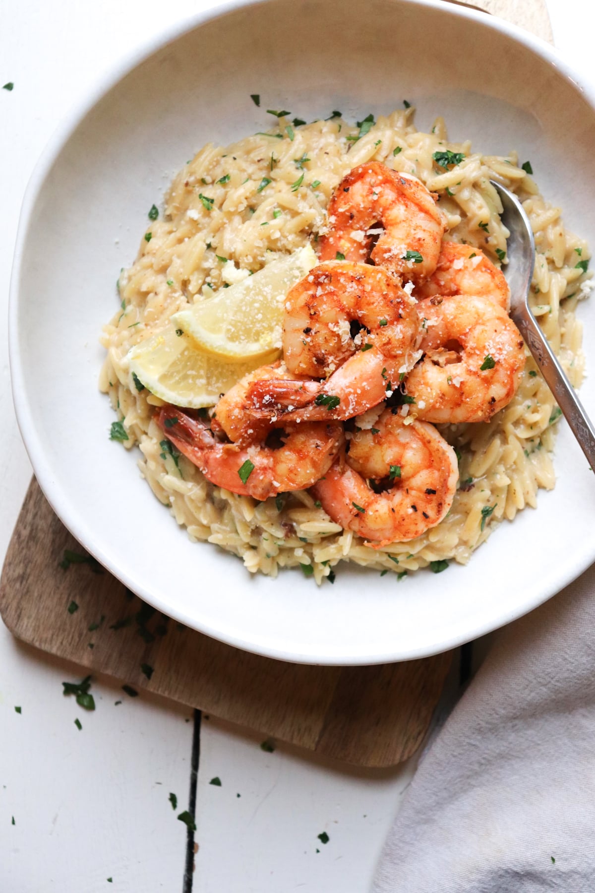 shrimp orzo pasta in bowl on wooden cutting board.